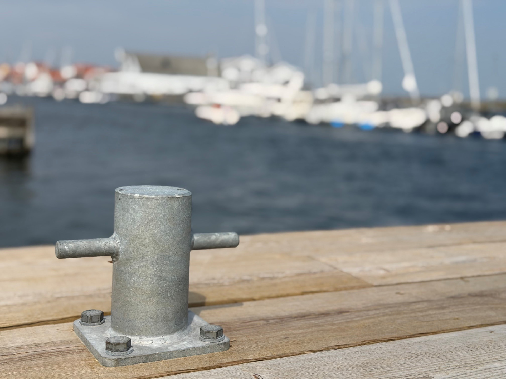 Brygga i bohuslänsk hamn med förtöjningspollare, båtar och sjöbodar